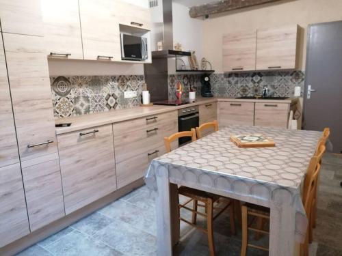 une cuisine avec une table et des chaises et une cuisine avec des placards en bois dans l'établissement Agréable maison de village., à Castellane