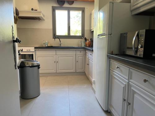 une cuisine avec des armoires blanches, un évier et une fenêtre dans l'établissement Villa Cazat Rozat, à Saint-Paul-en-Forêt