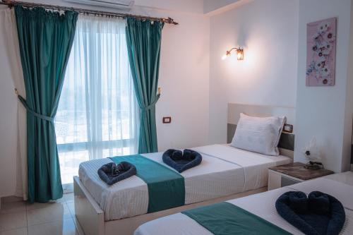 two beds in a room with green curtains and a window at Swiss Royal DAHAB in Dahab