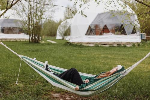 a woman laying in a hammock in a field at Czorsztyn Glamp in Maniowy