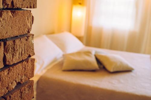 a bed with two pillows sitting next to a brick wall at Agriturismo Sweet Cottage in Marina di Grosseto