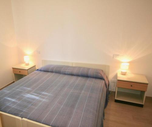 1 dormitorio con 1 cama y 2 mesitas de noche con lámparas en DUNA FIORITA PREMIUM en Lignano Sabbiadoro