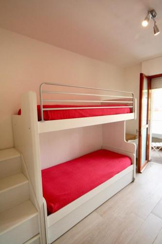 1 dormitorio con 2 literas con sábanas rojas en DUNA FIORITA PREMIUM en Lignano Sabbiadoro