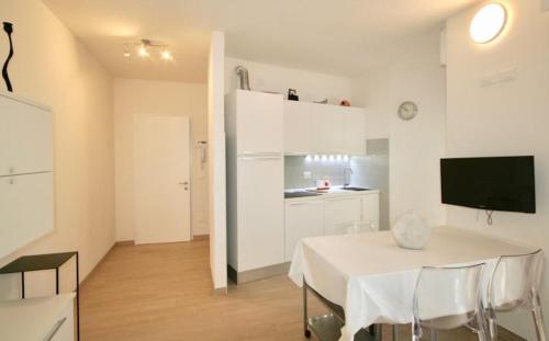 Habitación blanca con mesa y cocina en DUNA FIORITA PREMIUM en Lignano Sabbiadoro