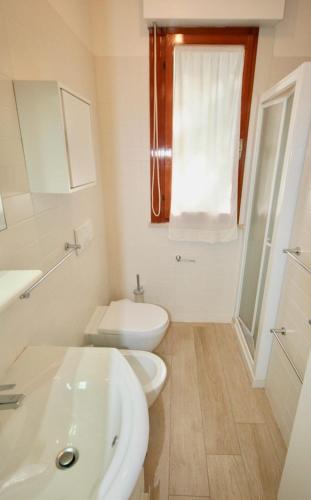 Baño blanco con lavabo y aseo en DUNA FIORITA PREMIUM en Lignano Sabbiadoro