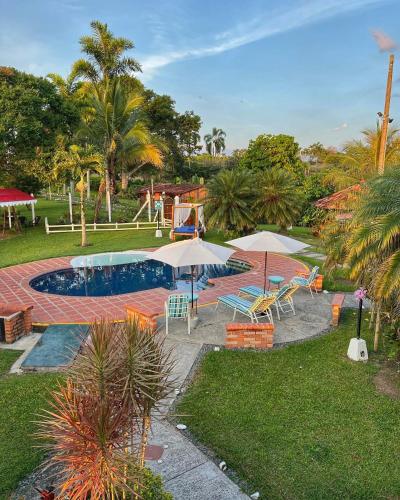 une piscine avec des parasols et des chaises ainsi qu'une aire de jeux dans l'établissement Casa Lemar, à Quimbaya