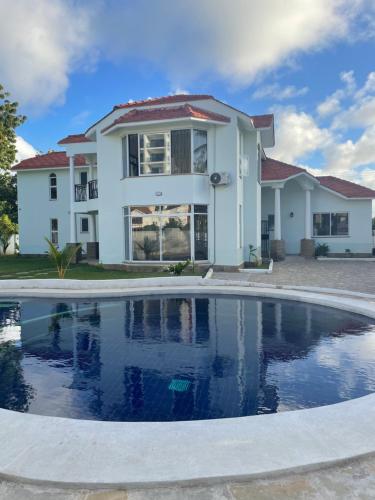 a house with a swimming pool in front of a house at Villa Macheo in Mombasa