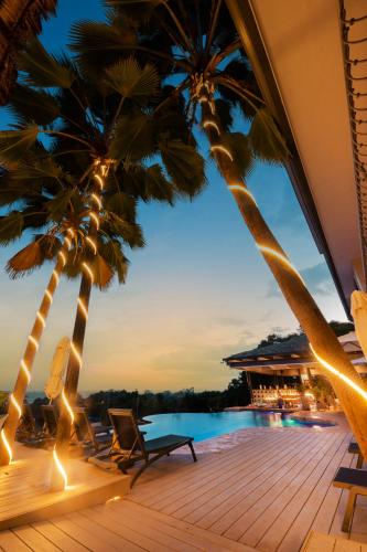 a resort with palm trees and a swimming pool at Marala Hotel in Esterillos