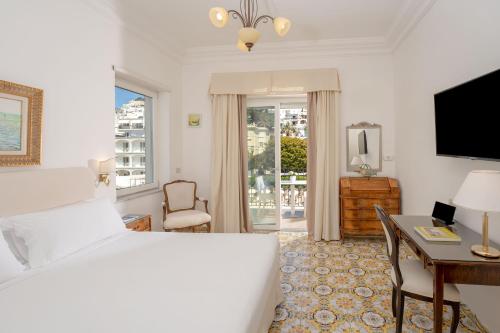 a bedroom with a bed and a desk and a television at Hotel Syrene in Capri