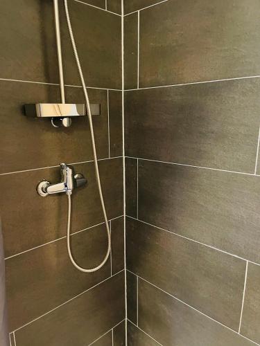 a shower with a hose attached to a tiled wall at City Studios mit Garten in Elberfeld- Zentral - Nespresso - Netflix in Wuppertal