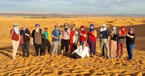 a group of people standing in the desert at Sunset Camp Merzouga in Merzouga