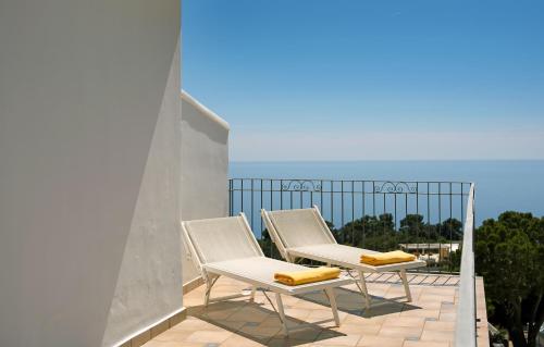 two chairs on a balcony with a view of the ocean at Hotel Syrene in Capri