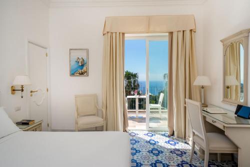 a hotel room with a bed and a desk with a view at Hotel Syrene in Capri