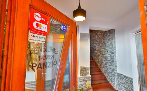 an orange door in a building with a sign on it at Pensiunea Janosi - Janosi Panzio, Janosi Olga PFA in Praid