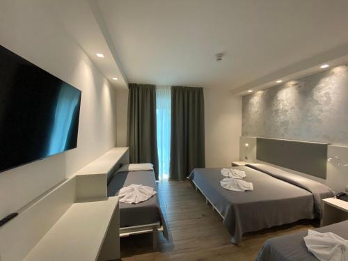 um quarto de hotel com duas camas e uma televisão de ecrã plano em Hotel Aldebaran em Lido di Jesolo