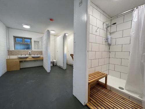 a bathroom with two sinks and a shower and a bench at Glamping at Camp Corve in Chale