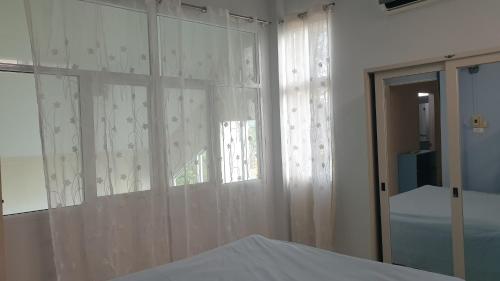 a bedroom with white curtains and a window at บ้านOrman in Chumphon