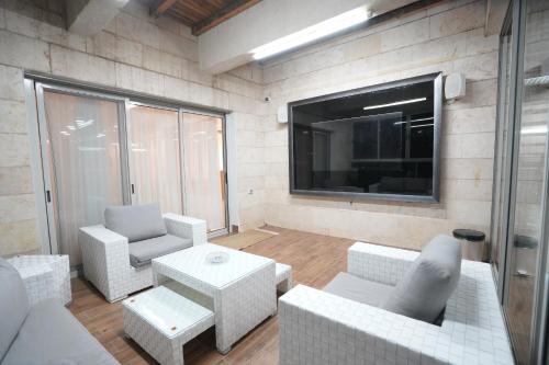 a living room with white furniture and a flat screen tv at סויטת החלומות in Ashkelon