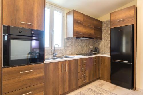 a kitchen with wooden cabinets and a black refrigerator at Vasilikis Sea House in Lefkímmi
