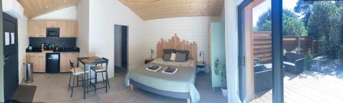 Una habitación con una cama y una cocina en una casa en Les ptits nids du Lac en Lacanau