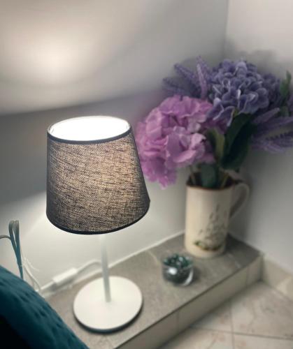 a lamp on a table next to a vase of purple flowers at Bellevue Herculaneum B&B in Ercolano