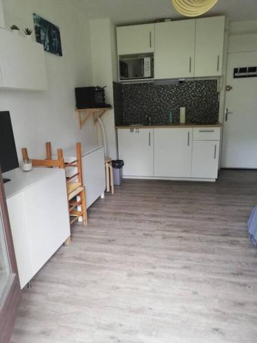 une cuisine avec des armoires blanches et un plancher en bois dans l'établissement Studio 4 personnes, aux Angles