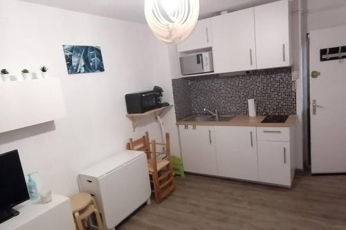 une cuisine avec des armoires blanches et un évier dans l'établissement Studio 4 personnes, aux Angles