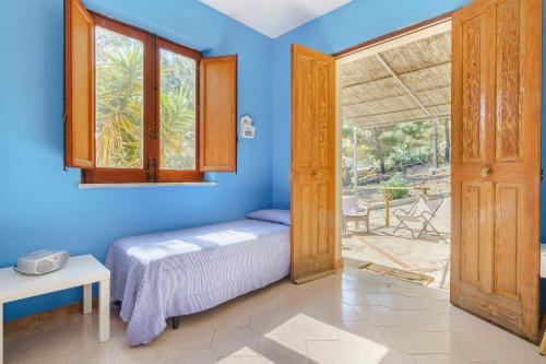 um quarto com paredes azuis e uma cama e uma porta em La Pineta al Mare em Érice