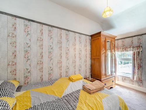 a bedroom with two beds and a wall with floral wallpaper at Lilac Cottage in Grosmont