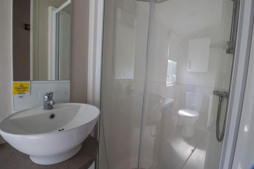 a white bathroom with a sink and a shower at Great Caravan With Decking Southview Holiday Park In Skegness Ref 33002v in Skegness