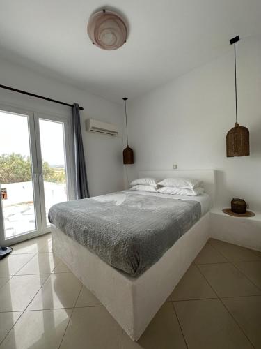 a white bedroom with a bed and a large window at Naxian Touch in Agia Anna Naxos