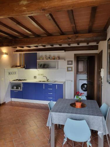 a kitchen with blue cabinets and a table and chairs at Villa Torricelli Scarperia - Il Giardinetto Residence in Scarperia