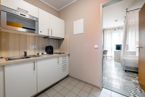 a kitchen with white cabinets and a sink at Aparthotel Alma Bonn in Bonn