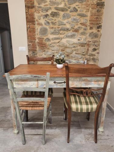 a wooden table with two chairs and a stone wall at Villa Torricelli Scarperia - Il Giardinetto Residence in Scarperia