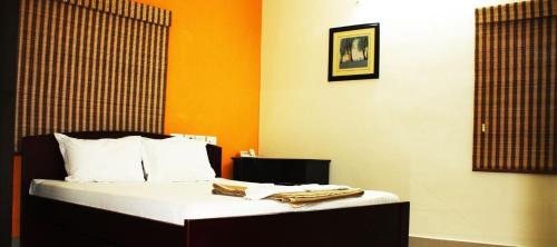 um quarto com uma cama com lençóis brancos e paredes cor-de-laranja em GUINDY CHENNAI STAYS em Chennai