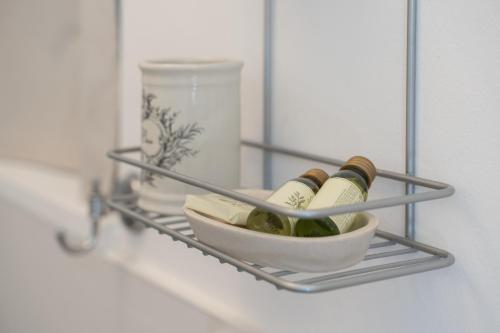 a shelf with three bottles of wine and a bowl at Dimora Santa Caterina in Polignano a Mare