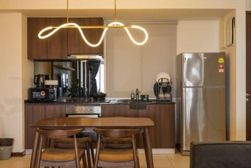 a kitchen with a table and a stainless steel refrigerator at Deluxe Seaview Suite King Bed by The Only Bnb in Tanjong Tokong