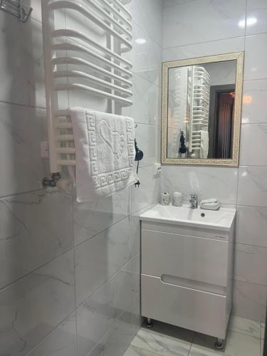 a white bathroom with a sink and a mirror at Мелодія Гір .Апартаменти з видом на гори . in Vorokhta