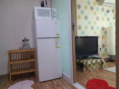 a white refrigerator in a room with a tv at Cozy accomodation near chilgok gyeongdae hospital in Daegu