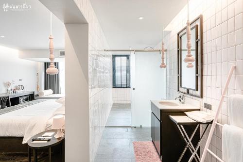 a white bathroom with a bed and a sink at SOOKNIRUND HOTEL in Chiang Rai