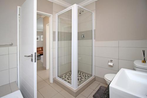 uma casa de banho com um chuveiro e um WC. em White Orchid Luxury Apartment em Chartwell