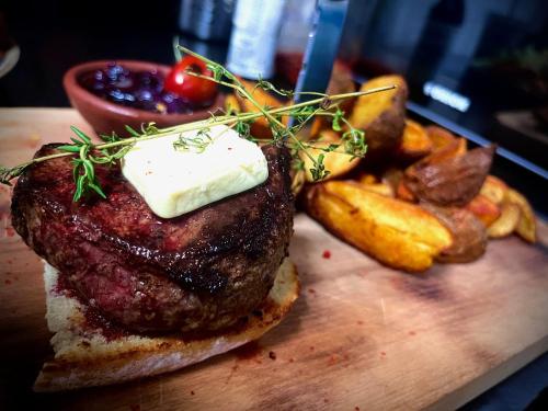a steak sandwich and french fries on a cutting board at Pensiunea Janosi - Janosi Panzio, Janosi Olga PFA in Praid