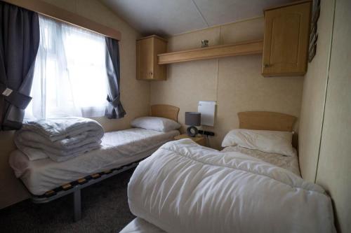 a room with three beds and a window at 6 Berth Caravan With Decking Nearby Clacton-on-sea Ref 46128v in Great Clacton
