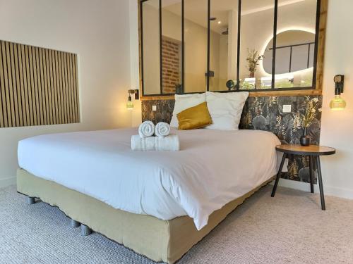 une chambre avec un grand lit avec deux serviettes dessus dans l'établissement Le Jardin Secret - Piscine - Clim - Haut de gamme, à Albi