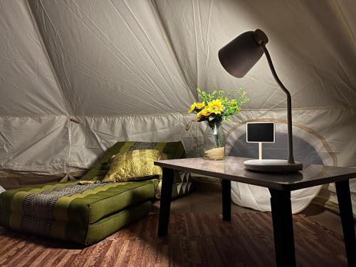 a table with a lamp and a couch in a tent at The Hidden Gem in Ban Nok