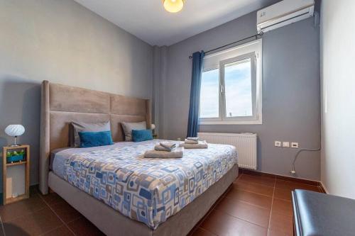 a bedroom with a bed with blue pillows and a window at MegaLuxe Apartment in Heraklio Town