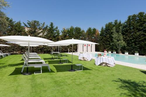 a group of chairs and umbrellas next to a pool at Appia Antica Hotel in Corato