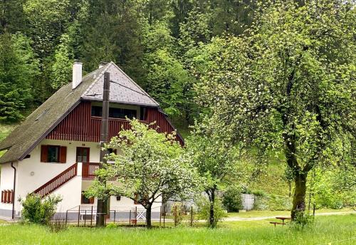 une maison rouge et blanche dans un champ arboré dans l'établissement Apartment Joži, à Vallée de la Soča