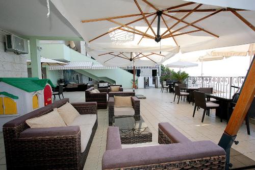 an outdoor patio with couches and tables and umbrellas at Montesan Luxury Apartment Beach Front in Sveti Stefan
