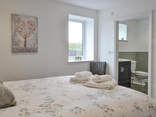- une chambre blanche avec un lit et des serviettes dans l'établissement Old Byre Cottage - Uk43377, à Kirklinton